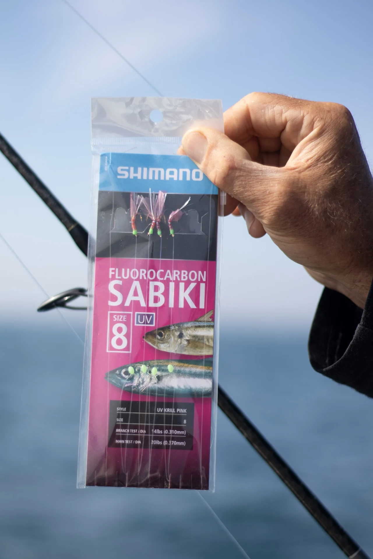 Hand holding a packaged sabiki bait rig aboard a boat.